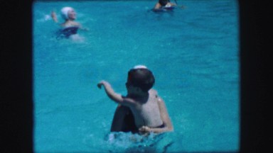 1957: Mother son swimming bouncing spinning in calming blue waters. GLEN, NEW