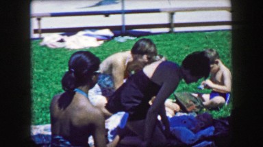 1957: Big multiracial family friends enjoying public pool summertime relaxation.
