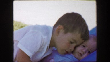 1957: Brother cuddling nuzzle against baby boy brother smushed face. GLEN, NEW