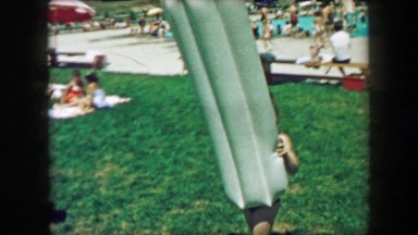 1957: Boy carries inflatable pool floating raft at public pool recreation place.