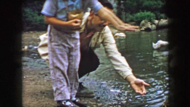 1957: Father son team feeding ducks in small residential wetland pond. GLEN, NEW