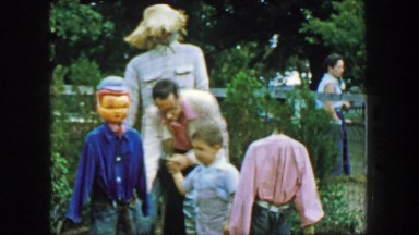 1957: Father son playing autumn festival headless scarecrow display. GLEN, NEW
