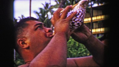 1958: Hawaiian sunset ceremony performance man blowing conch shell horn.