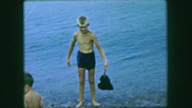 1959: Boy carrying Atlantic horseshoe crab tail grab beach summer. CAPE COD,