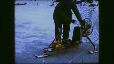 1961: Man Starting Fan Hovercraft Ski Vehicle Over Winter Frozen Ice Pond