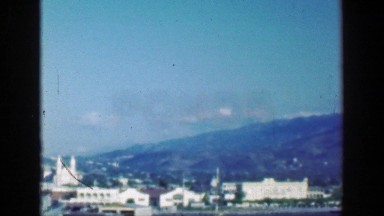 1953: Tropical island steep cliff mountains paradise city green rugged ecology.