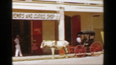 1953: Downtown colonial style old western horse drawn wagon caribbean setting.