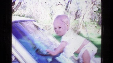 1957: Newborn Baby Standing and Crawling on Car Hood Window Play Summer Day