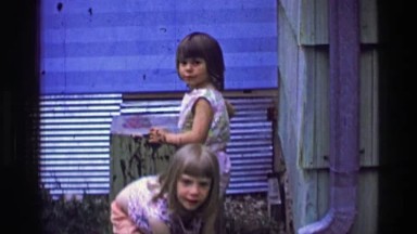 1957: Sisters playing clean mud table surface making art summer vacation. BATON
