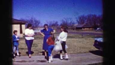 1961: children hugging and kissing various people outside in the driveway IOWA