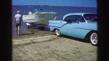 1961: blue car backs boat into body of water as someone watches and helps IOWA
