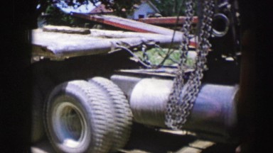 1961: a red truck carrying heavy chains is parked in a yard of a rural area IOWA