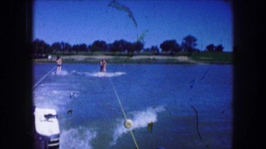 1961: two water skiers carefully crossing the wake as the boat putters just fast