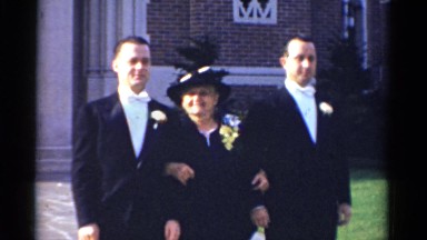 1943: the scene is an outdoor scene showing a mother holding arms of her son