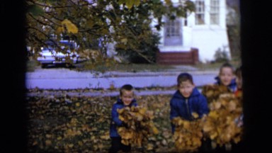1964: four young children playing joyfully together in the autumn leaves CAMDEN,