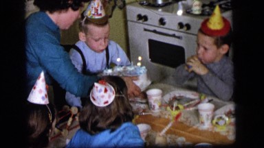 1964: the scene shows a party, a birthday party a kid is seen blowing candles