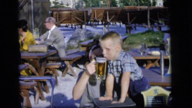 1964: a young woman giving a small boy a taste of beer from a mug CAMDEN