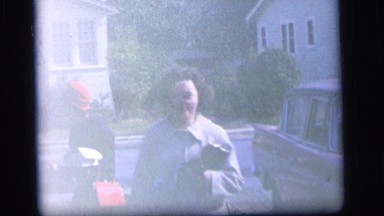 1964: woman smiling while a few kids wait for the ice cream man. very old cars
