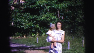 1979: Mother Holding Daughter in Arms Walking Outdoors