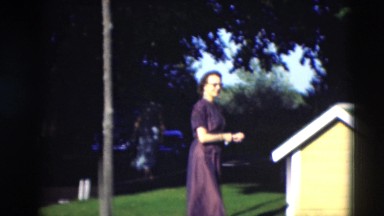 1951: well dressed people gathering in yard in front of a yellow dog house