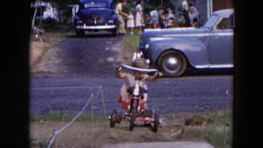 1954: Blonde girl trying to make her tricycle go HICKSVILLE, NEW YORK
