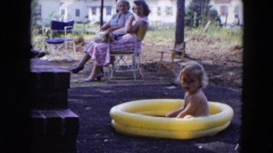 1954: family relaxing in the backyard while a child plays HICKSVILLE, NEW YORK