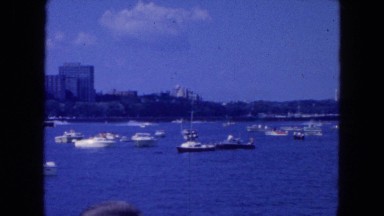 1954: regatta yacht club sails on clear day in a blue bay with clock tower