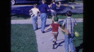 1954: a group of small boys walking down a sidewalk and crossing the street