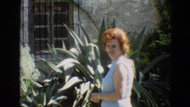 1968: A Woman Wandering and Verifying in a Garden with Full Plants