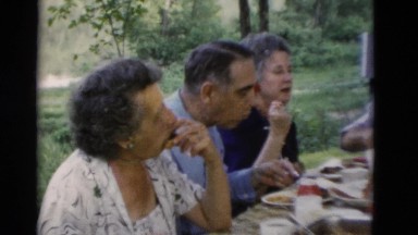 1949: group of older people having a meal and talking outdoors around a table