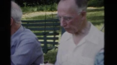 1949: elderly man and elderly women sitting at a table outside eating food