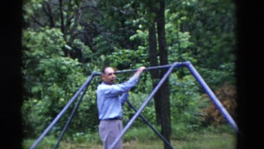 1949: a person is seen adjusting a swing and testing by holding his weight on it