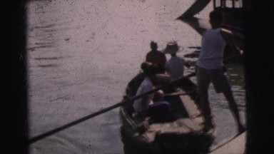 1962: man navigating a small wooden boat through the water