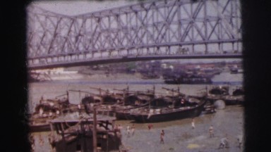 1962: a large group of ships anchored under the city bridge. BANGKOK, THAILAND