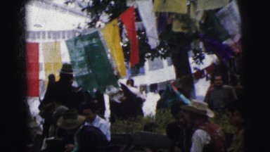 1962: a large gathering of people at a festival decorated with colorful flags