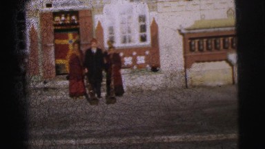 1962: three elaborately dressed people posing in front of a unique building