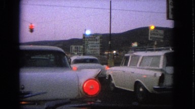 1963: various cars stopped for a single bright red light dangling in the air