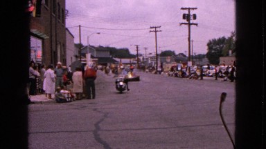 1963: a festive parade with a marching band and crowds gathered on either side