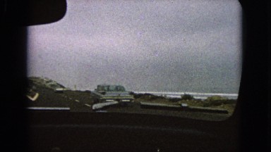 1963: a shot of the rugged coastline through the front window of a moving