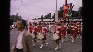 1963: town people marching drumming parade near local restaurant diner