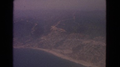 1963: aerial view of land and water captured while recording in an airplane
