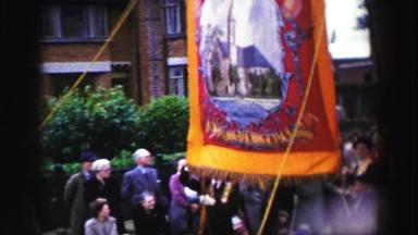 1952: Four People Carry Flag in English Street Parade