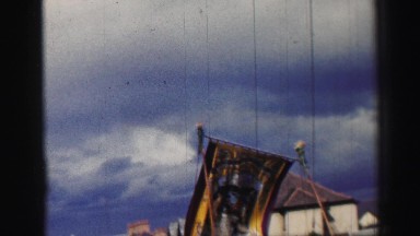 1952: the scene shows a flag being marched along people and has beautiful clouds
