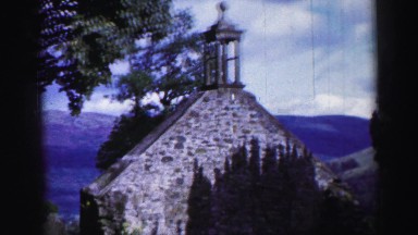 1952: stone building against a beautiful countryside view with mountains in the