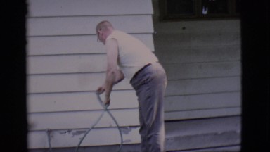 1966: Older gentleman walking outside of his house with pet.CLARKDALE, ARIZONA