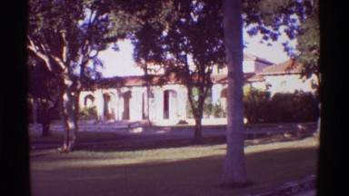 1971: View of a large boy of water set against a mountain and a building among