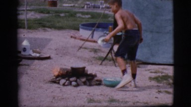 1968: Young Boy Cooking Meal Over Heated Stones at Campsite in Cottonwood, Arizona