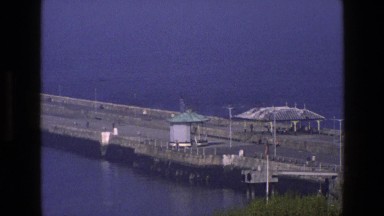 1969: a small gazebo on a large, long pier surrounded by beautiful blue water