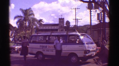 1971: Man Stands Outside Van Beside Street in Tropical Hawaii