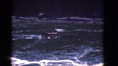 1964: a small boat traveling down a vast rushing river with a large waterfall